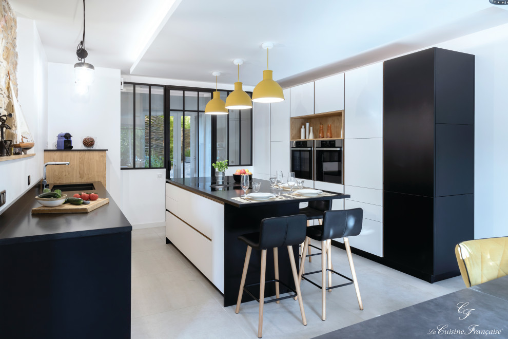 Photo of a medium sized contemporary enclosed kitchen in Rennes with flat-panel cabinets, white cabinets, granite worktops, ceramic flooring, an island and black worktops.