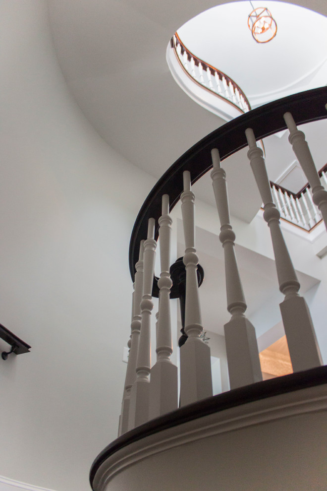 Large transitional wood spiral staircase in DC Metro with wood risers and wood railing.