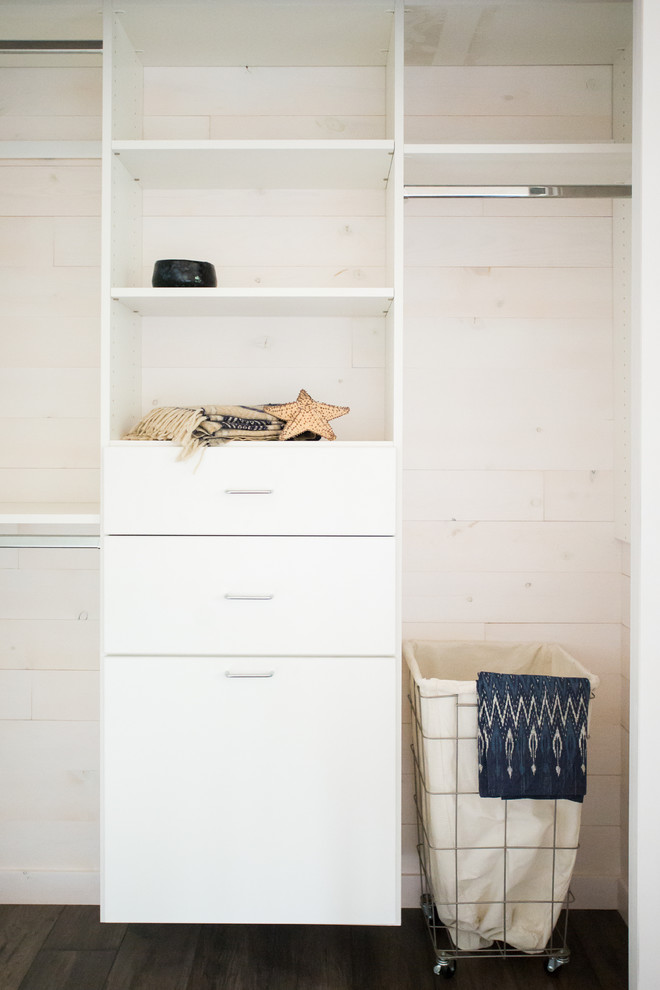 This is an example of a small beach style gender-neutral built-in wardrobe in Minneapolis with flat-panel cabinets, white cabinets and dark hardwood floors.