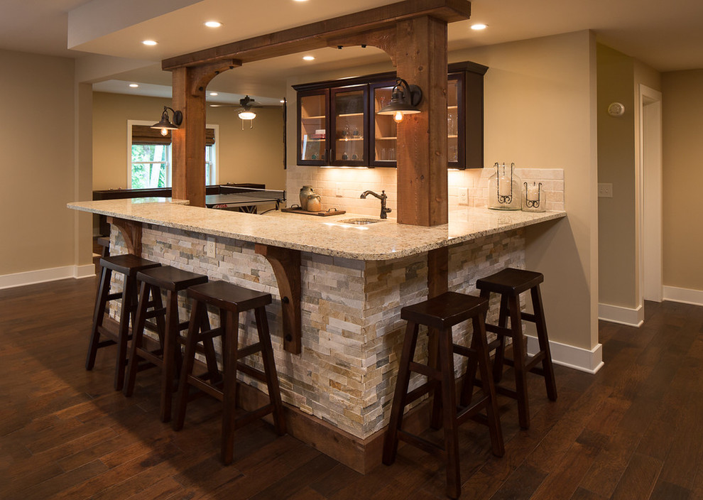 This is an example of a mid-sized country l-shaped wet bar in Atlanta with an undermount sink, shaker cabinets, dark wood cabinets, granite benchtops, beige splashback, stone tile splashback and dark hardwood floors.