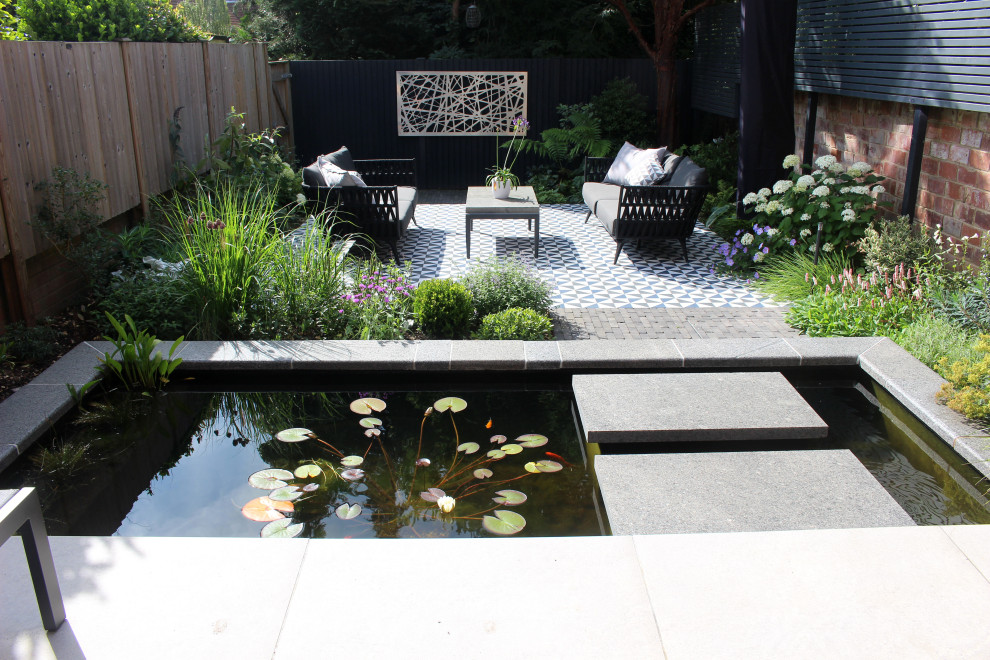 Small contemporary courtyard patio in Hampshire with natural stone pavers and an awning.