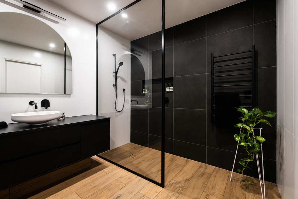 Large contemporary bathroom in Melbourne with an open shower, white tile, ceramic tile, black walls, porcelain floors, a vessel sink, engineered quartz benchtops, brown floor, an open shower and black benchtops.