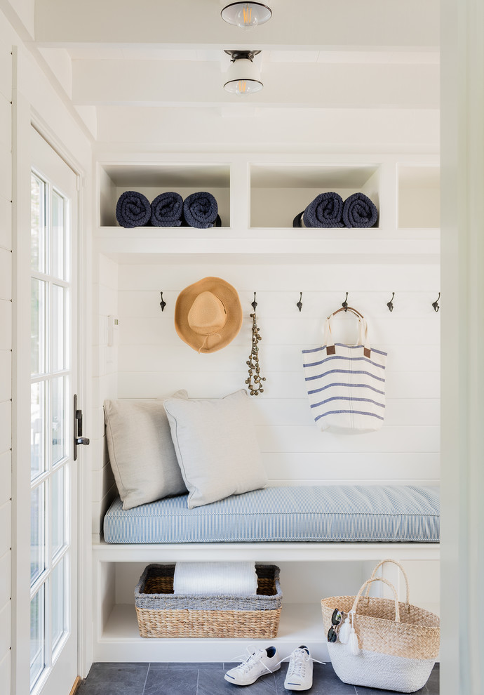 Design ideas for a beach style mudroom in Boston with white walls and black floor.