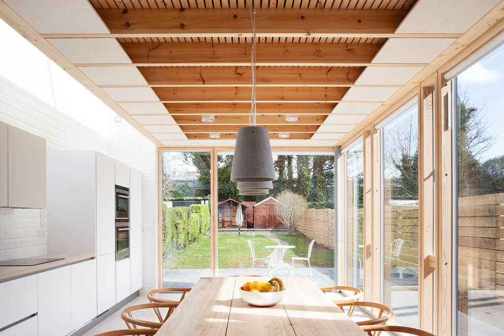 Inspiration for a mid-sized scandinavian single-wall eat-in kitchen in Dublin with flat-panel cabinets, white cabinets, laminate benchtops, white splashback, ceramic splashback, porcelain floors and no island.