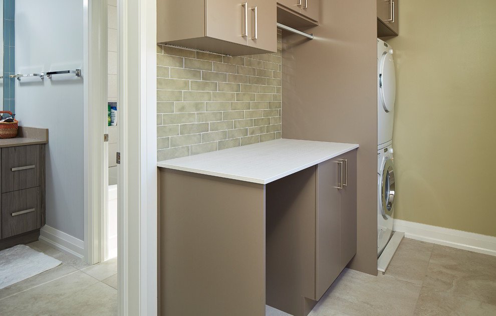 Inspiration for a mid-sized contemporary single-wall laundry room in Toronto with flat-panel cabinets, brown cabinets, quartzite benchtops, beige walls, ceramic floors, a stacked washer and dryer and beige floor.