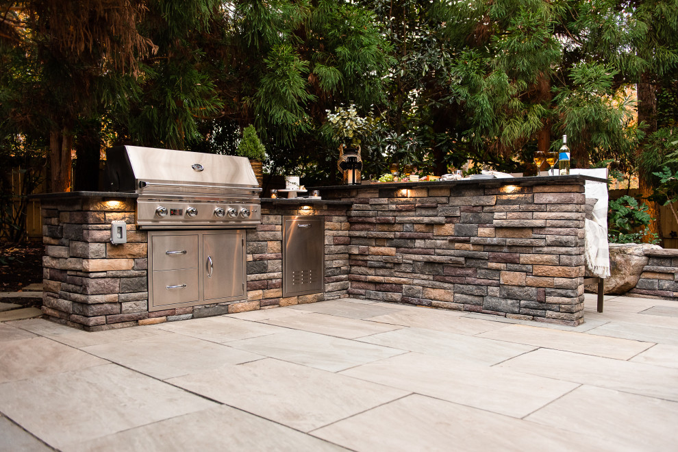 Photo of a mid-sized modern backyard patio in Richmond with an outdoor kitchen and natural stone pavers.