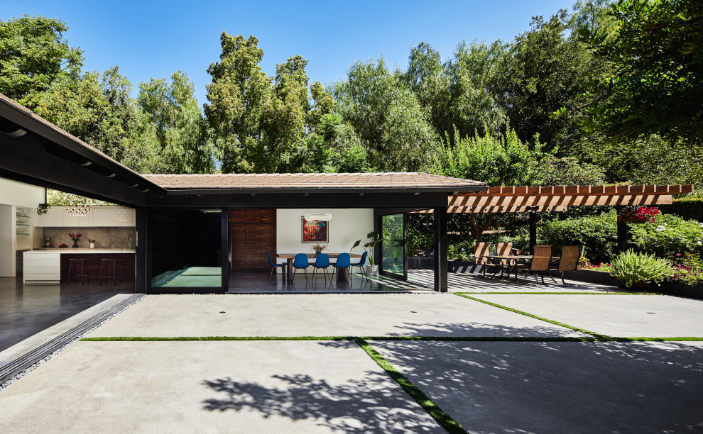 Expansive midcentury one-storey stucco black house exterior in Los Angeles with a gable roof and a tile roof.