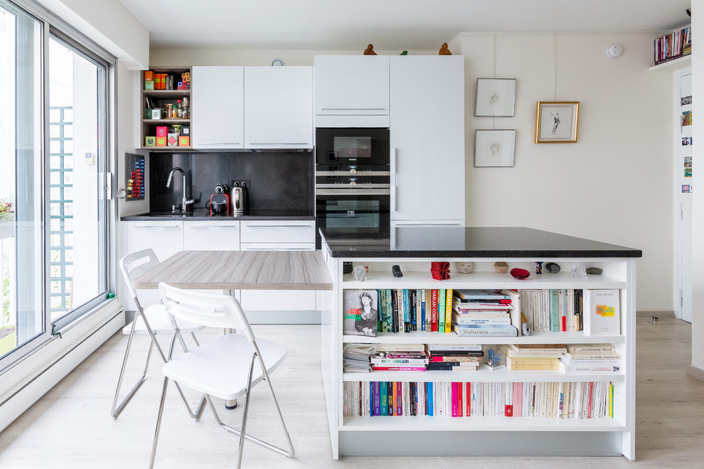 This is an example of a large contemporary galley eat-in kitchen in Paris with white cabinets, black splashback, panelled appliances, light hardwood floors and with island.