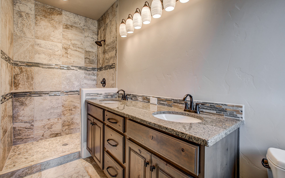 This is an example of a mid-sized transitional master bathroom in Denver with raised-panel cabinets, medium wood cabinets, an alcove shower, beige tile, travertine, beige walls, travertine floors, an undermount sink and granite benchtops.