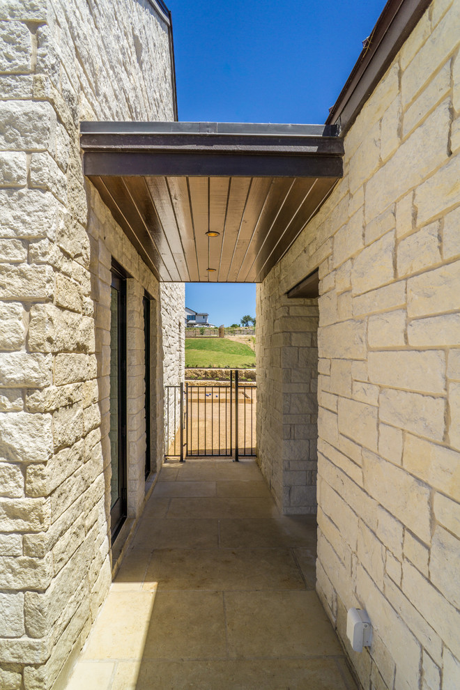 Large country one-storey white house exterior in Austin with stone veneer, a shed roof and a metal roof.