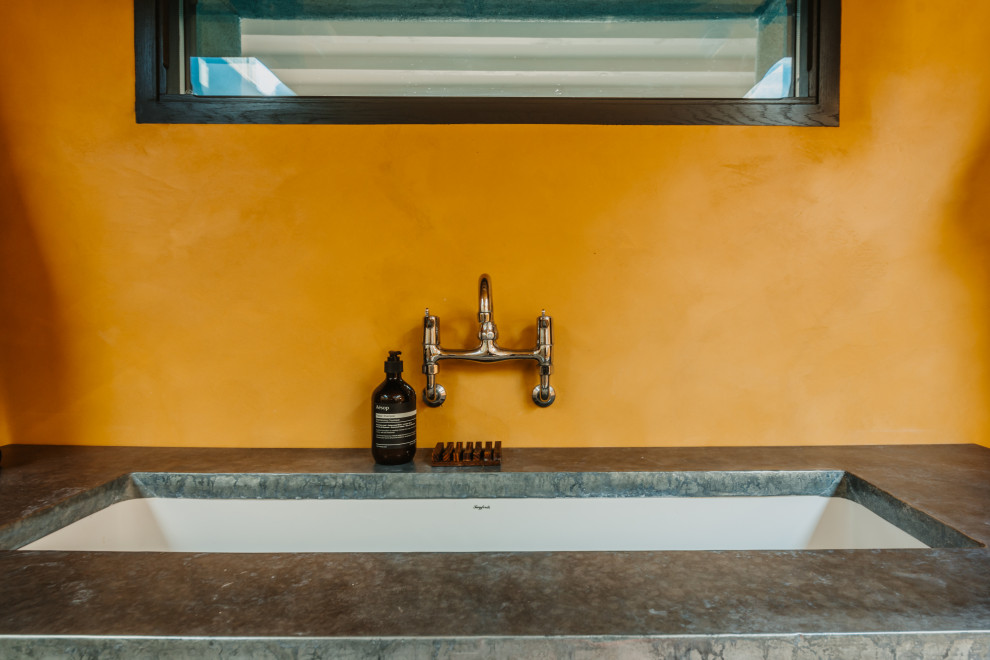 This is an example of a mid-sized beach style 3/4 bathroom in Cornwall with orange walls, cement tiles, zinc benchtops and grey floor.