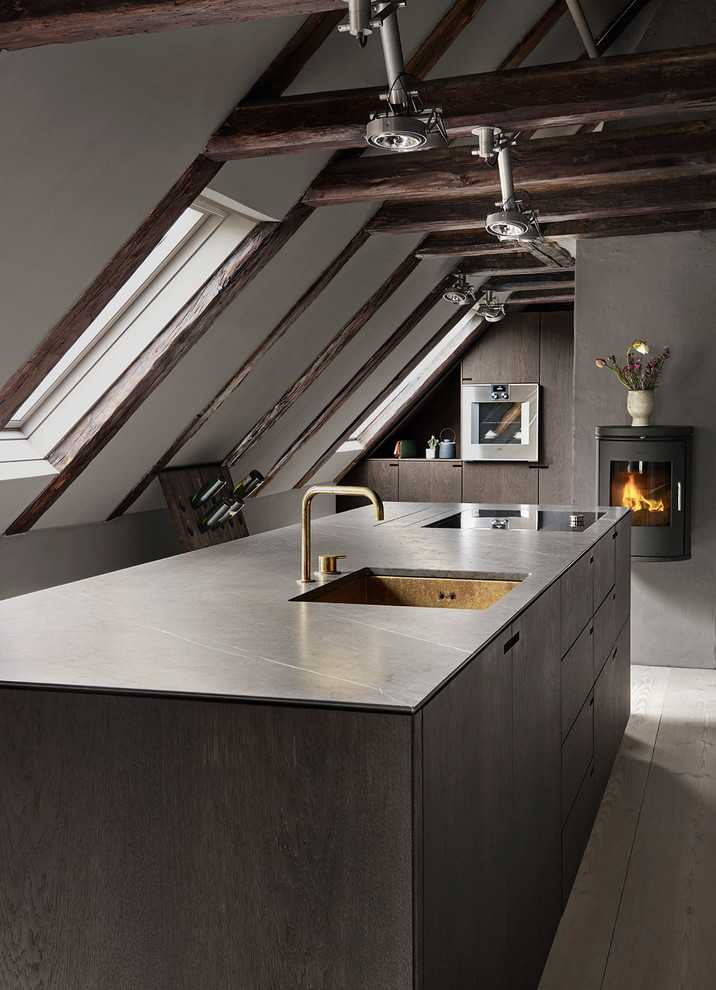 This is an example of a large scandinavian l-shaped eat-in kitchen in Copenhagen with a single-bowl sink, flat-panel cabinets, dark wood cabinets, marble benchtops, black appliances, light hardwood floors, with island and grey floor.