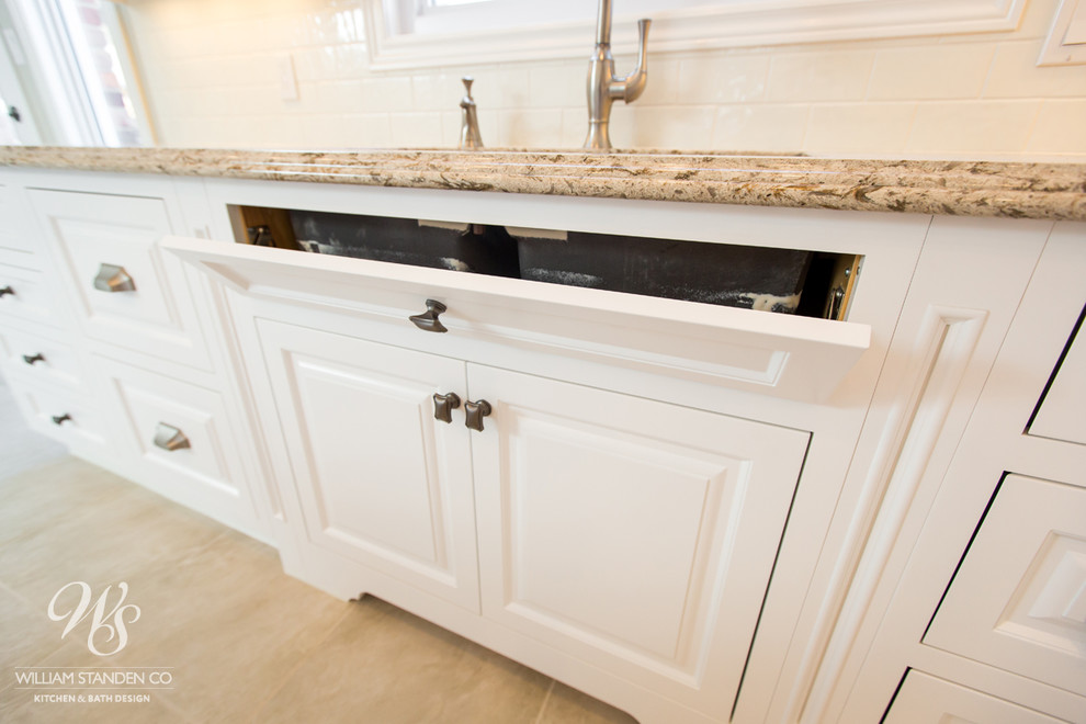 Eat-in kitchen - mid-sized transitional u-shaped porcelain tile eat-in kitchen idea in Toronto with an undermount sink, raised-panel cabinets, white cabinets, quartzite countertops, beige backsplash, stone slab backsplash, stainless steel appliances and an island