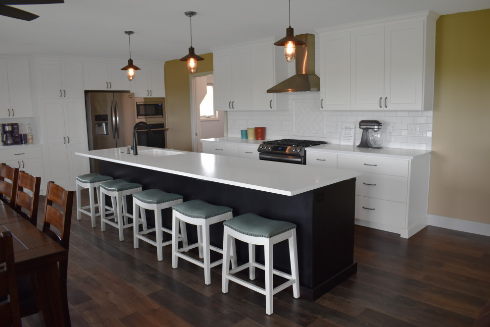 Open concept kitchen - large modern l-shaped vinyl floor and brown floor open concept kitchen idea with a drop-in sink, yellow cabinets, quartzite countertops, yellow backsplash, subway tile backsplash, stainless steel appliances, an island and white countertops