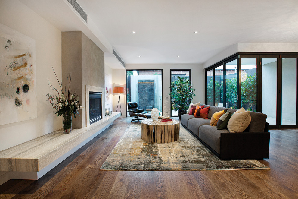 Inspiration for a large contemporary open concept living room in Melbourne with medium hardwood floors, a stone fireplace surround, a wood stove and no tv.