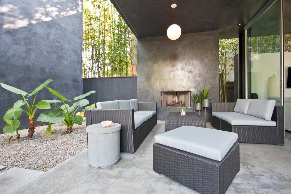 Design ideas for a mid-sized contemporary courtyard patio in Los Angeles with a fire feature, concrete slab and a roof extension.