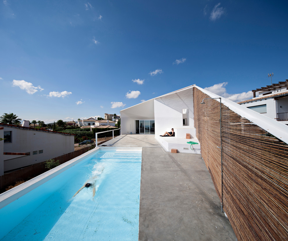 Inspiration for a mid-sized industrial rooftop rectangular lap pool in Malaga with a pool house and stamped concrete.