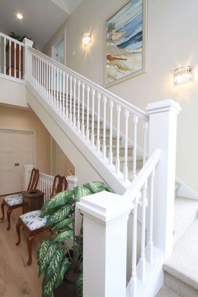 This is an example of a country carpeted straight staircase in Grand Rapids with carpet risers and wood railing.