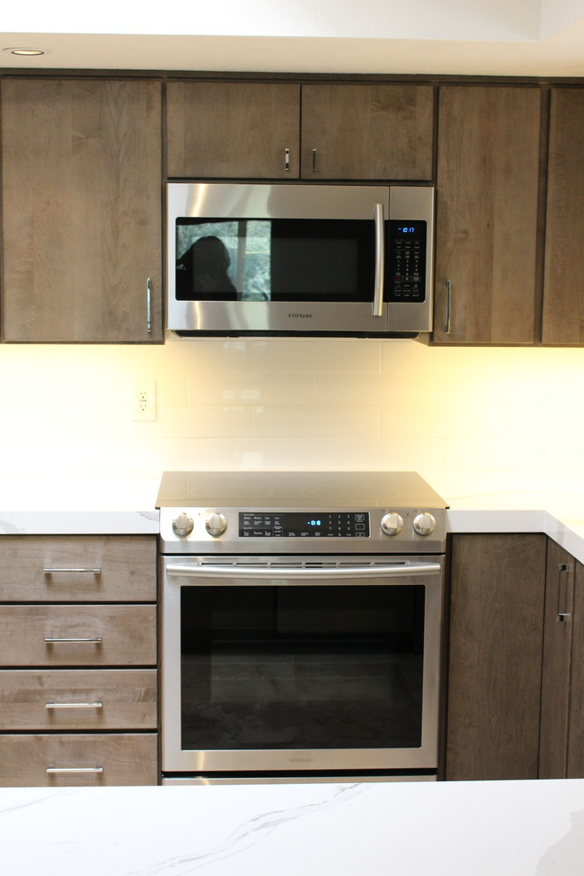 Inspiration for a mid-sized transitional u-shaped ceramic tile open concept kitchen remodel in Phoenix with an undermount sink, flat-panel cabinets, gray cabinets, quartz countertops, white backsplash, porcelain backsplash, stainless steel appliances and a peninsula