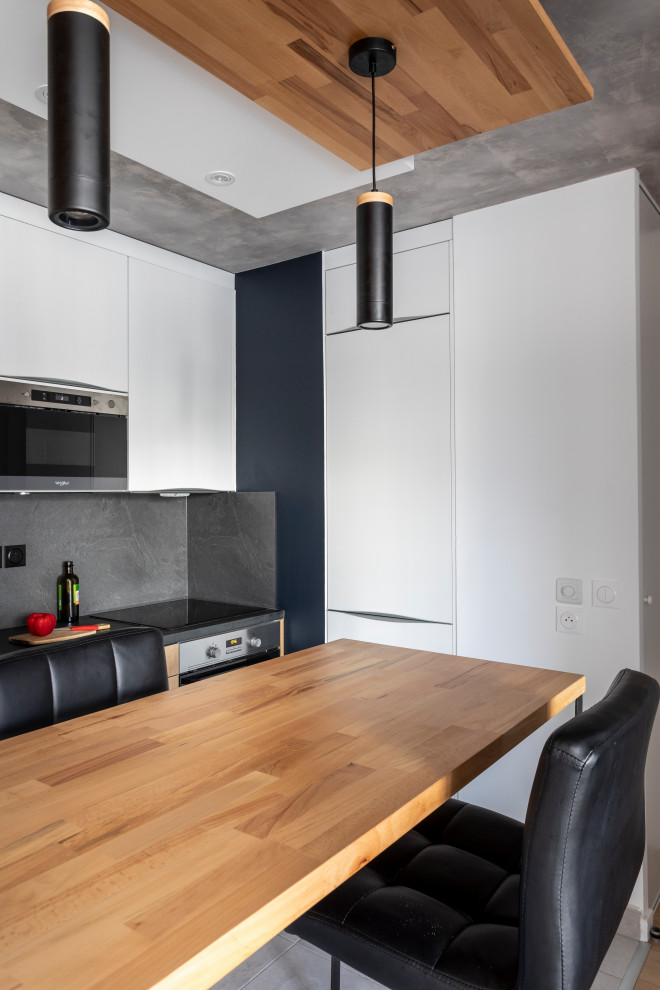 Foto på ett litet industriellt grå linjärt kök och matrum, med en undermonterad diskho, släta luckor, vita skåp, laminatbänkskiva, grått stänkskydd, rostfria vitvaror, klinkergolv i keramik, en köksö och grått golv