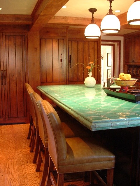 This is an example of a large traditional u-shaped kitchen pantry in Other with medium wood cabinets, tile benchtops, medium hardwood floors and with island.