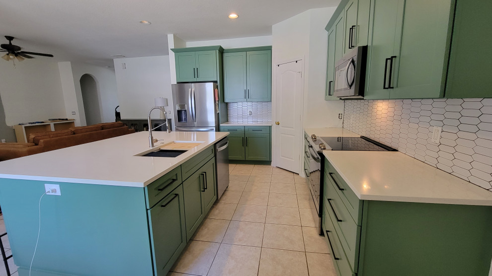 Inspiration for a mid-sized transitional l-shaped eat-in kitchen remodel in Orlando with shaker cabinets, green cabinets, quartz countertops, white backsplash, subway tile backsplash, an island and white countertops