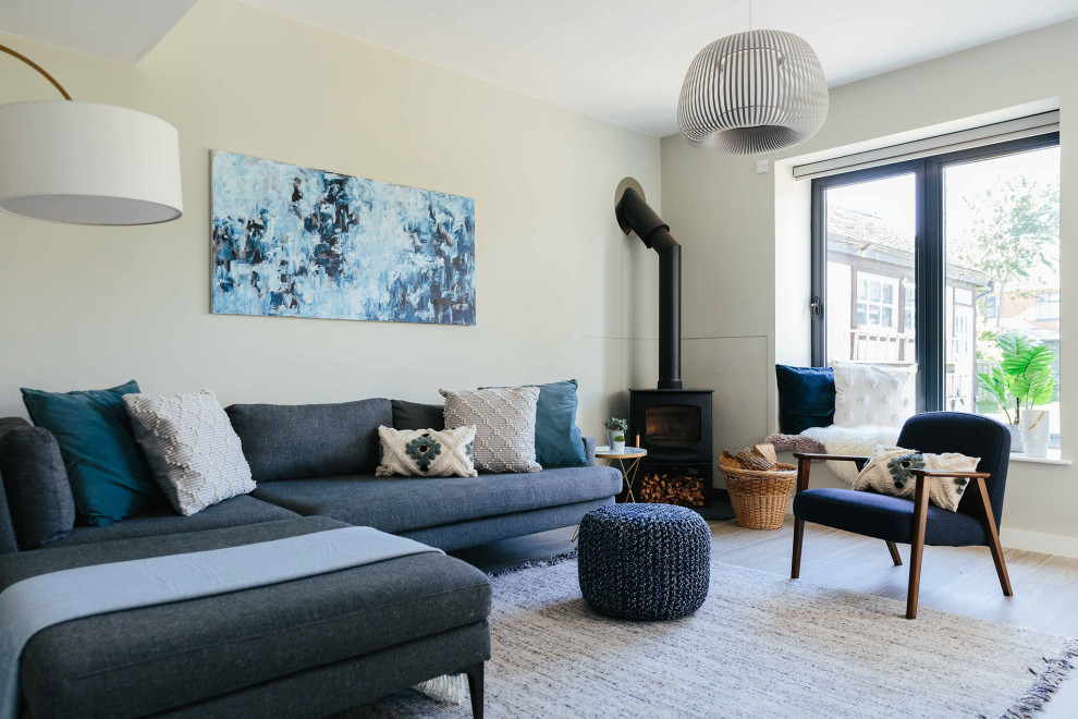 Idee per un soggiorno nordico di medie dimensioni e aperto con pareti grigie, parquet chiaro, stufa a legna, TV a parete e pavimento grigio