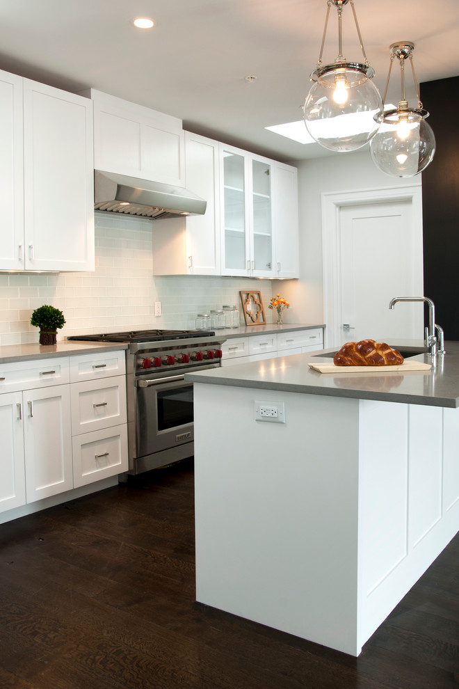 Photo of a mid-sized transitional galley eat-in kitchen in New York with a double-bowl sink, shaker cabinets, white cabinets, quartzite benchtops, white splashback, subway tile splashback, stainless steel appliances, medium hardwood floors and with island.