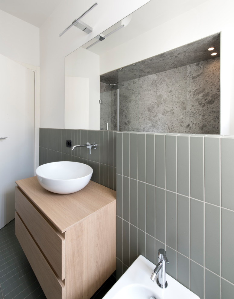 This is an example of a medium sized contemporary ensuite wet room bathroom in Milan with flat-panel cabinets, light wood cabinets, a submerged bath, a wall mounted toilet, green tiles, matchstick tiles, white walls, ceramic flooring, a vessel sink, wooden worktops, green floors, a hinged door, a wall niche, a single sink and a floating vanity unit.