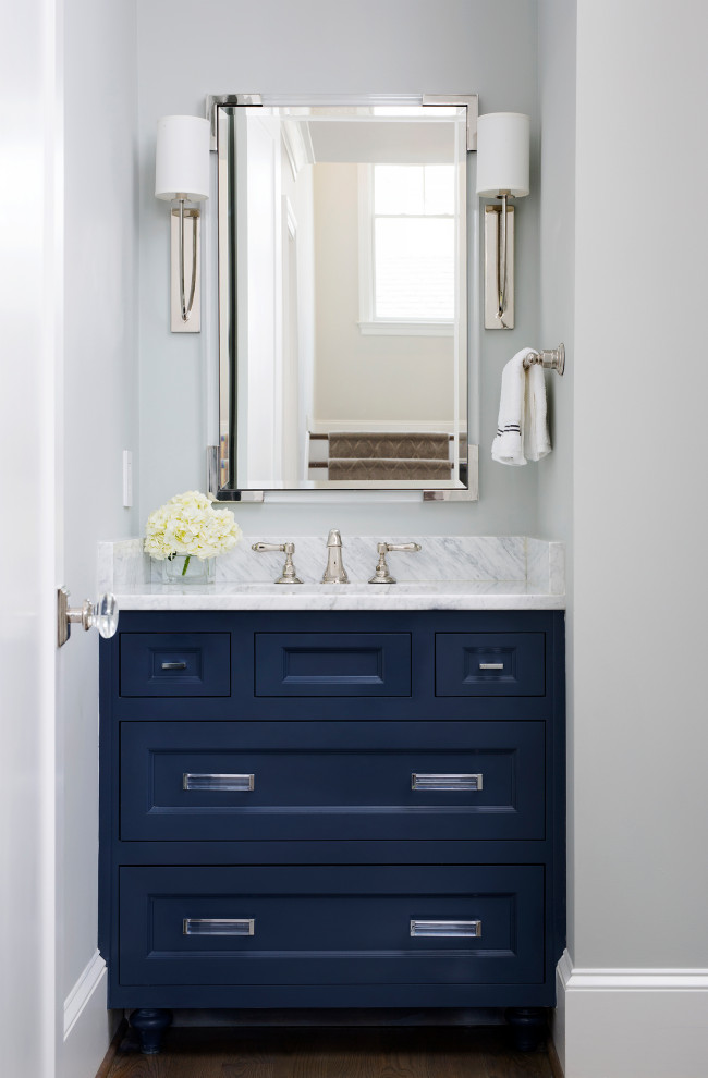 Example of a small transitional dark wood floor and brown floor powder room design in DC Metro with recessed-panel cabinets, blue cabinets, beige walls, an undermount sink, marble countertops and gray countertops