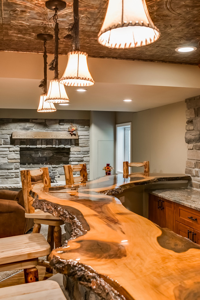 Design ideas for a large country look-out basement in Chicago with grey walls, medium hardwood floors, a standard fireplace, a stone fireplace surround and beige floor.