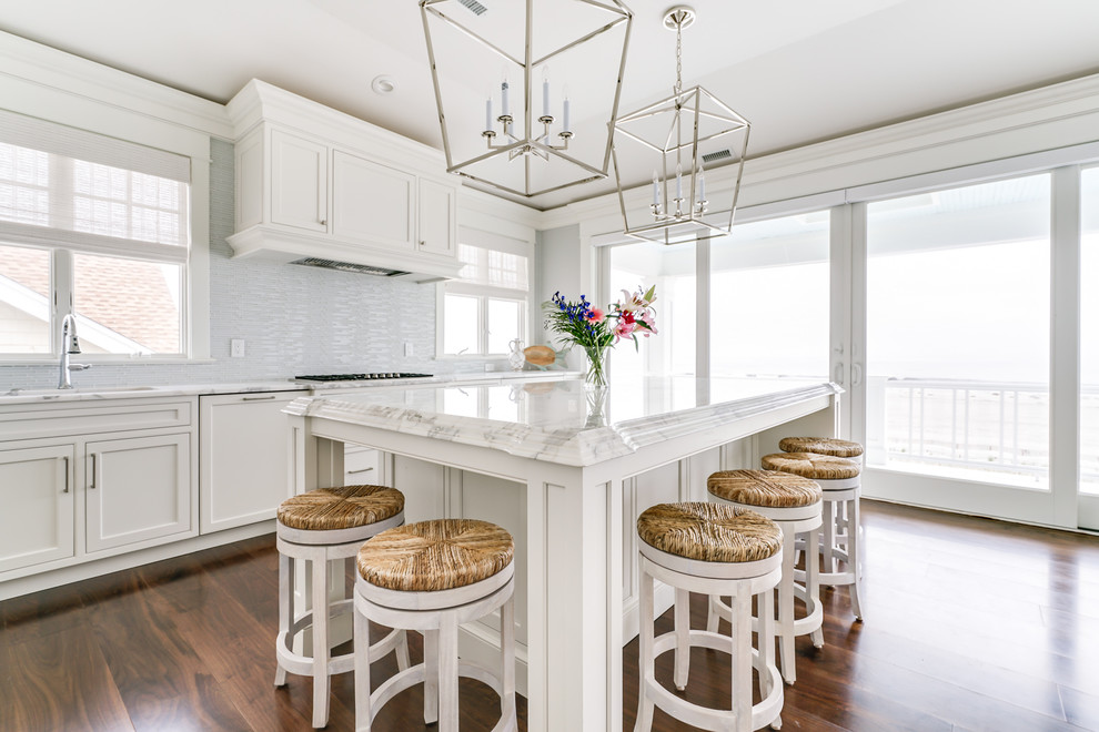 This is an example of a mid-sized transitional l-shaped eat-in kitchen in Philadelphia with an undermount sink, recessed-panel cabinets, white cabinets, marble benchtops, white splashback, panelled appliances, dark hardwood floors, with island and brown floor.