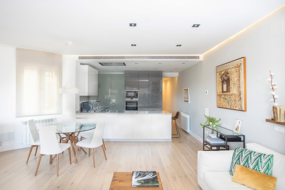 Imagen de sala de estar abierta moderna de tamaño medio con paredes blancas, suelo de baldosas de cerámica, todas las chimeneas, marco de chimenea de metal, televisor colgado en la pared y suelo marrón