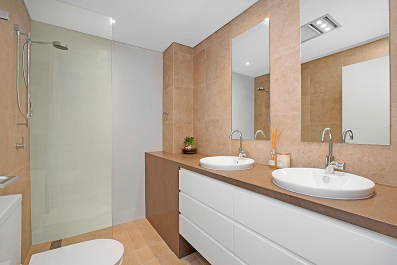 Inspiration for a mid-sized contemporary master bathroom in Sydney with flat-panel cabinets, white cabinets, a corner shower, a two-piece toilet, brown tile, limestone, limestone floors, an integrated sink, marble benchtops, brown floor and an open shower.