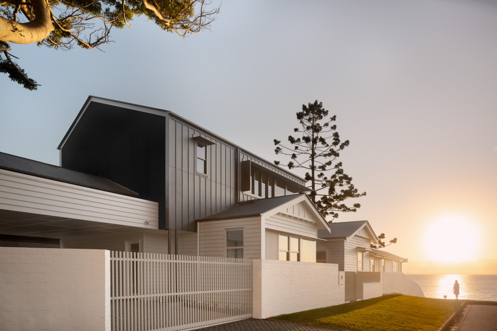 Cette photo montre une façade de maison multicolore chic à un étage avec un revêtement mixte et un toit gris.
