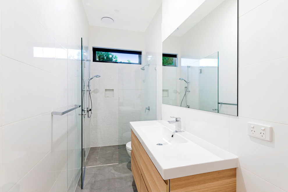 Design ideas for a small modern bathroom in Melbourne with furniture-like cabinets, light wood cabinets, a one-piece toilet, white tile, white walls, an integrated sink, ceramic tile and ceramic floors.