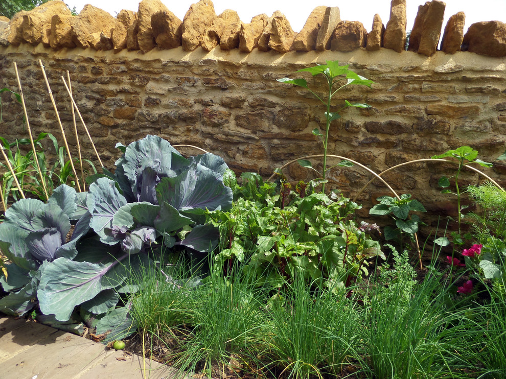 Photo of a small traditional sloped full sun garden for summer in Hertfordshire with a vegetable garden and natural stone pavers.