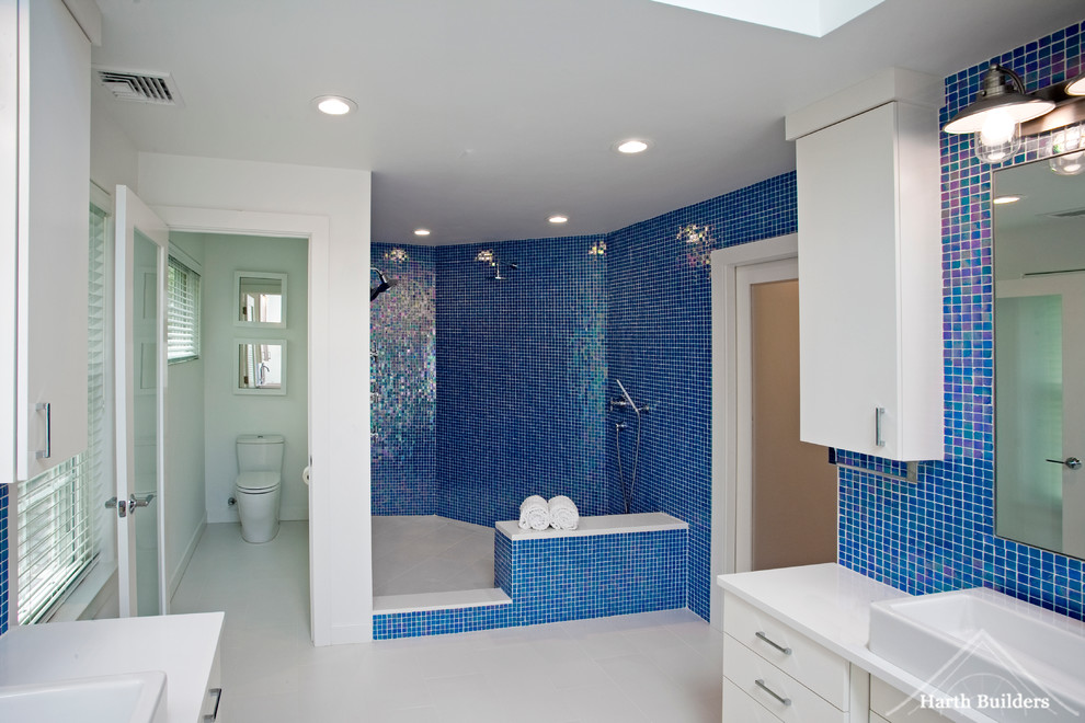 Photo of a large eclectic master bathroom in Philadelphia with a vessel sink, flat-panel cabinets, white cabinets, engineered quartz benchtops, a freestanding tub, an open shower, a one-piece toilet, blue tile, mosaic tile, white walls and porcelain floors.