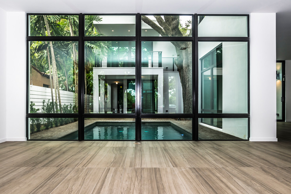 Photo of a mid-sized modern backyard rectangular pool in Miami with concrete slab.