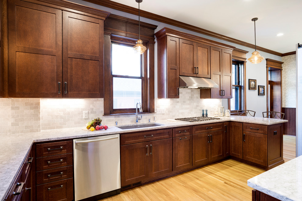 Design ideas for a large arts and crafts u-shaped eat-in kitchen in Minneapolis with an undermount sink, medium wood cabinets, quartz benchtops, marble splashback, stainless steel appliances, light hardwood floors, a peninsula, yellow floor, shaker cabinets and white splashback.