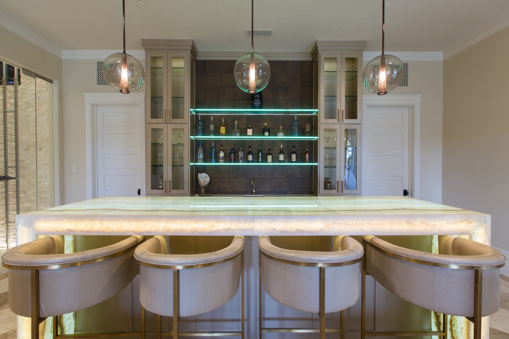 Photo of a large contemporary single-wall seated home bar in Dallas with an undermount sink, glass-front cabinets, beige cabinets, onyx benchtops, brown splashback and white benchtop.
