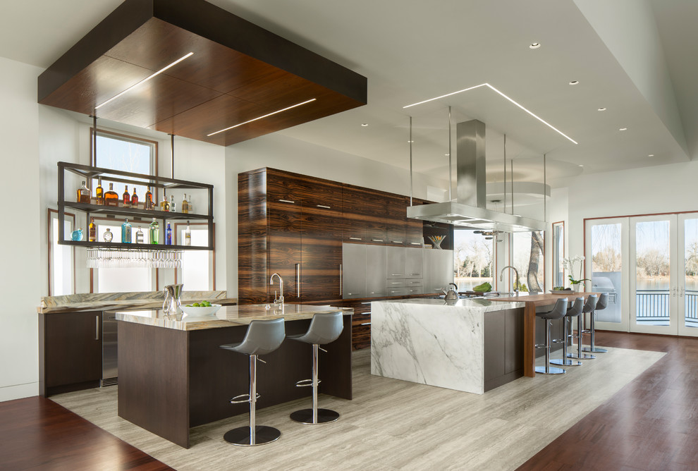 This is an example of a large contemporary galley open plan kitchen in Other with a farmhouse sink, flat-panel cabinets, dark wood cabinets, panelled appliances, porcelain floors, multiple islands, marble benchtops, beige floor and white benchtop.