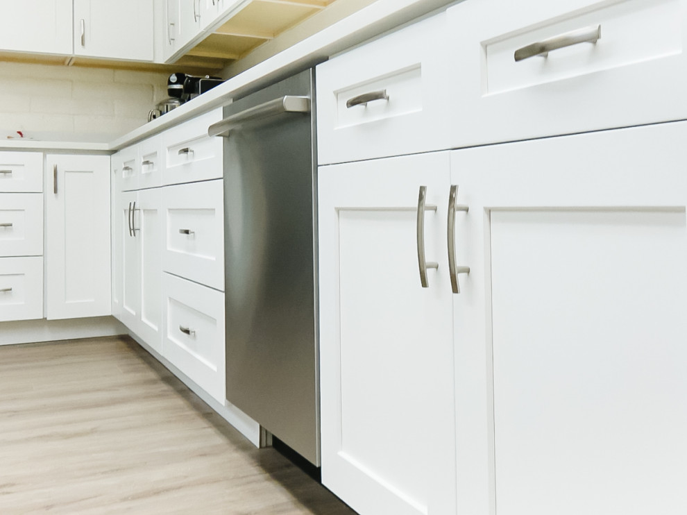 Photo of a mid-sized modern galley eat-in kitchen in Seattle with an undermount sink, shaker cabinets, white cabinets, laminate benchtops, white splashback, stone slab splashback, stainless steel appliances, vinyl floors, with island, brown floor, white benchtop and timber.
