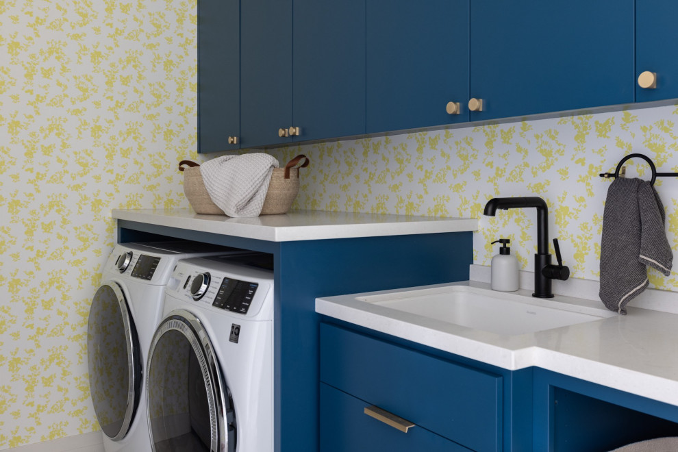 Photo of a medium sized contemporary single-wall utility room in San Francisco with a submerged sink, flat-panel cabinets, turquoise cabinets, engineered stone countertops, engineered quartz splashback, yellow walls, a side by side washer and dryer, white worktops and wallpapered walls.