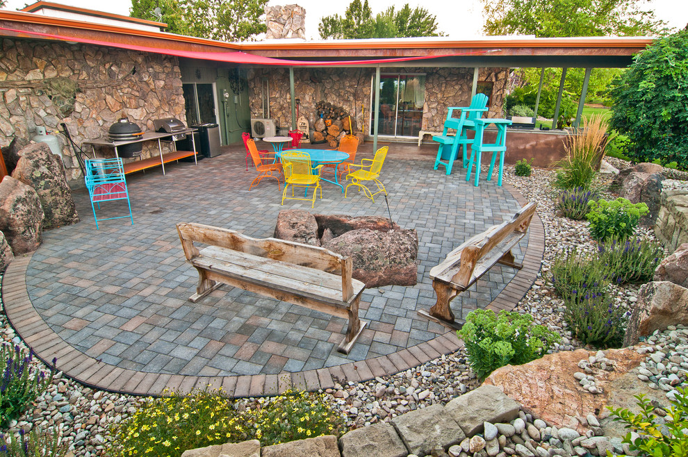 This is an example of an eclectic backyard patio in Boise with a fire feature, concrete pavers and an awning.
