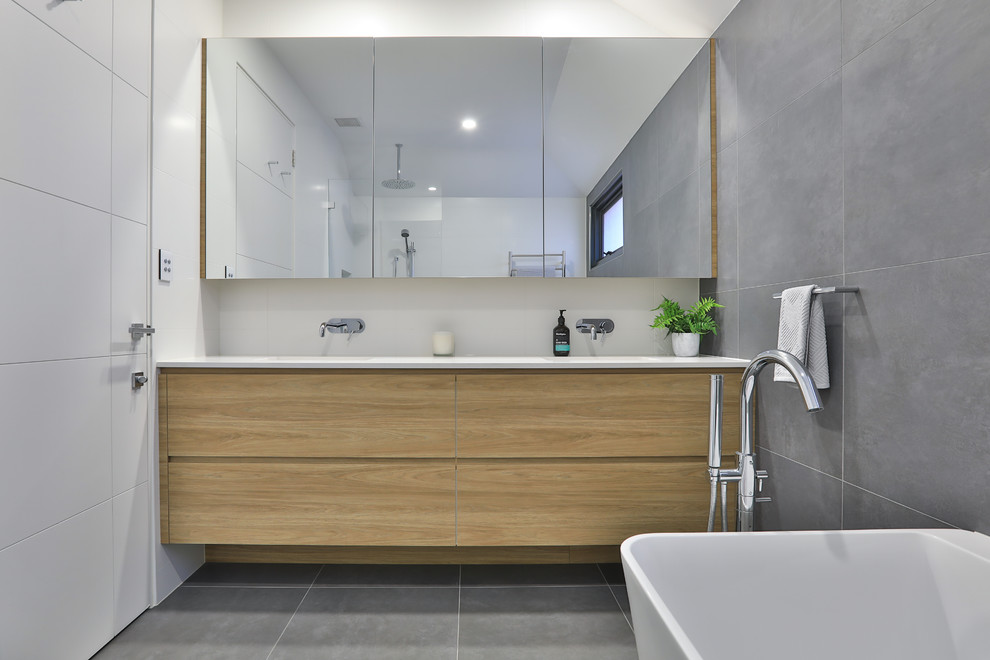 Inspiration for a large modern master bathroom in Sydney with flat-panel cabinets, light wood cabinets, a freestanding tub, white tile, ceramic tile, grey walls, ceramic floors, a wall-mount sink, engineered quartz benchtops, grey floor and white benchtops.