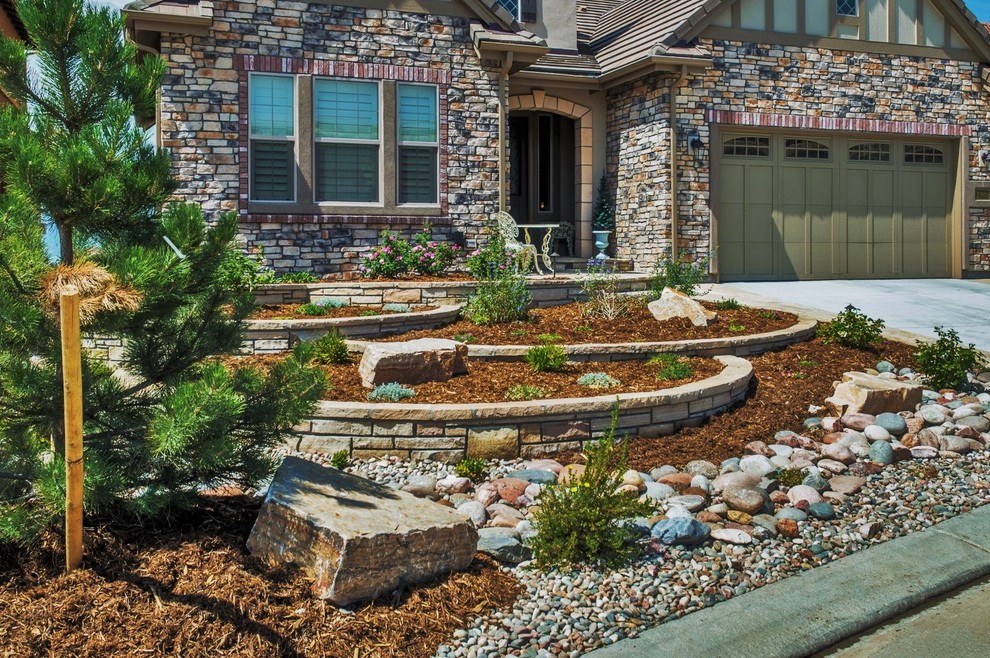 This is an example of a mid-sized contemporary front yard garden in Denver with a retaining wall and river rock.