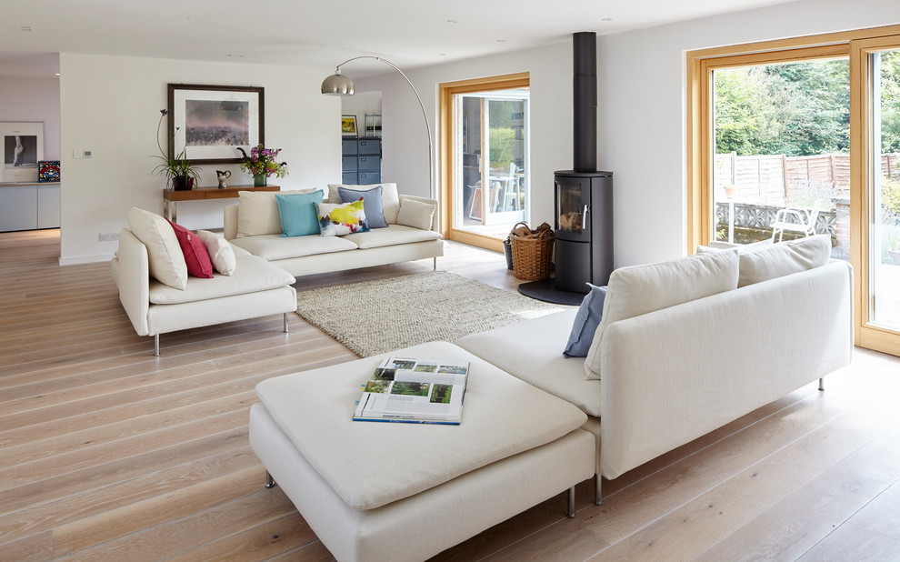 Inspiration for a large contemporary living room in Berkshire with light hardwood floors and a wood stove.
