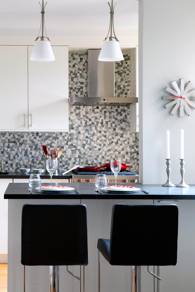 Contemporary l-shaped separate kitchen in New York with an undermount sink, white cabinets, granite benchtops, multi-coloured splashback, mosaic tile splashback, panelled appliances, a peninsula and black benchtop.