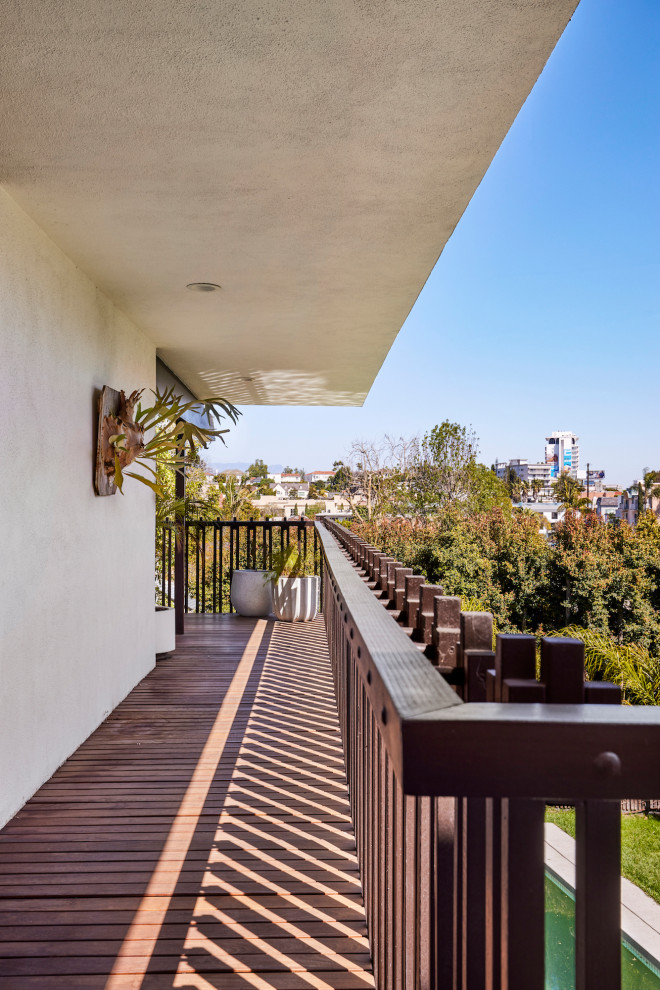 Inspiration for a large midcentury private wood railing balcony in Los Angeles with a roof extension.